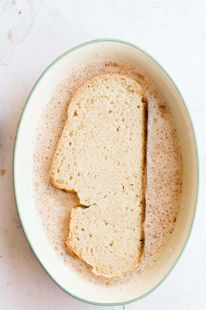 stale sourdough bread soaking in a vegan custard mixture to make French toast