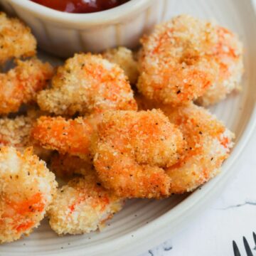 gluten free fried shrimp cooked in the air fryer served on a white plate with a white bowl of ketchup.
