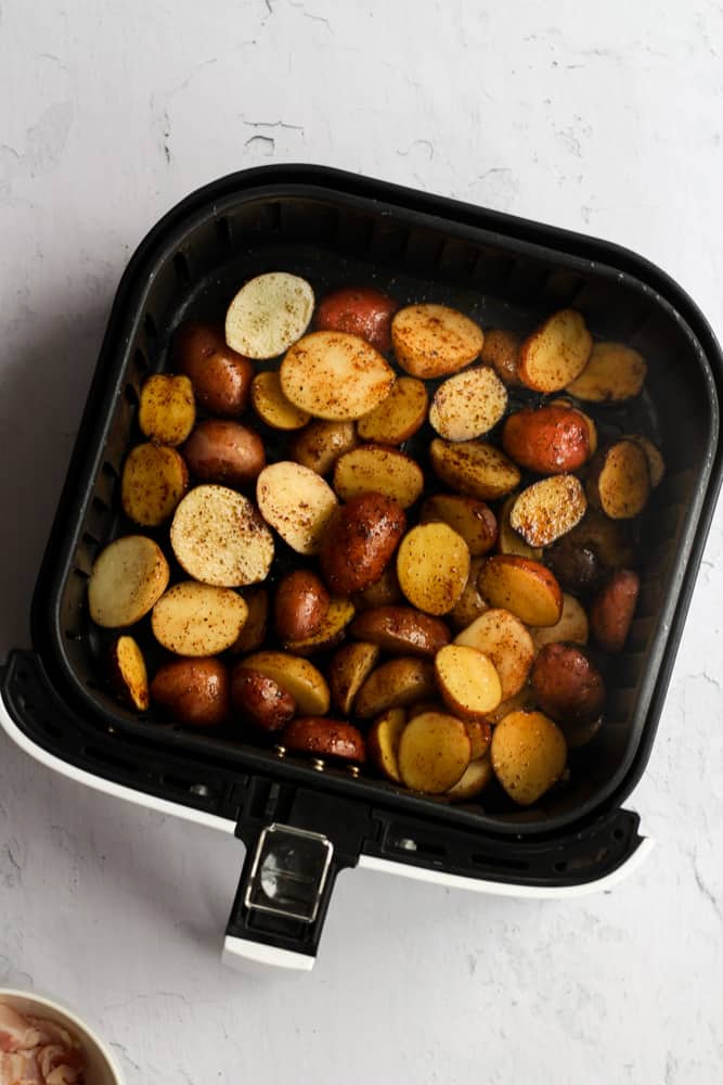 Baby potatoes in a single layer in a black air fryer basket