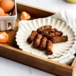air fryer breakfast sausage on a white plate inside a wood serving tray with handles.