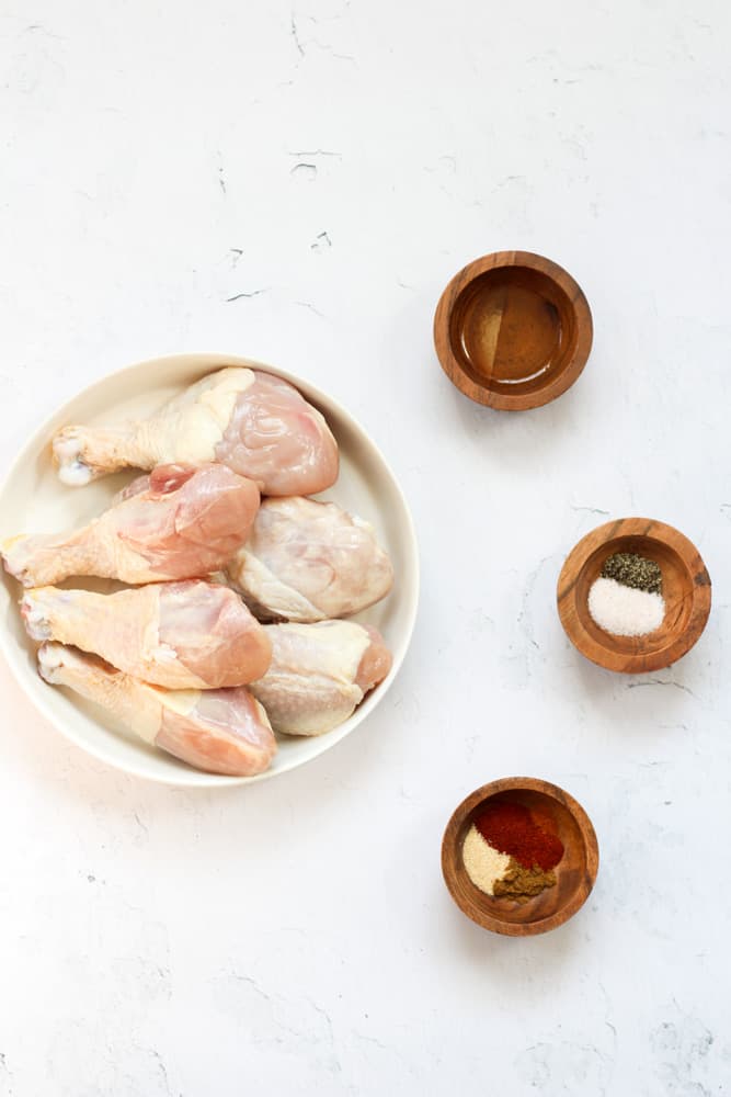 ingredients for air fryer chicken legs on a white backdrop.