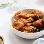 air fryer drumsticks in a white bowl on a white backdrop