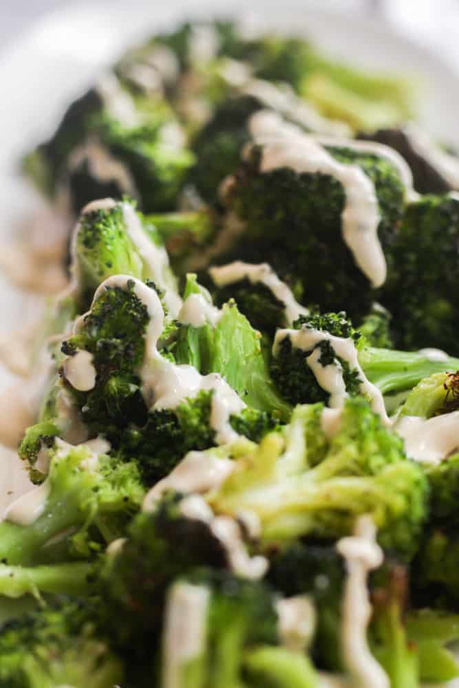 healthy broccoli cooked in the air fryer drizzled with a tahini sauce.