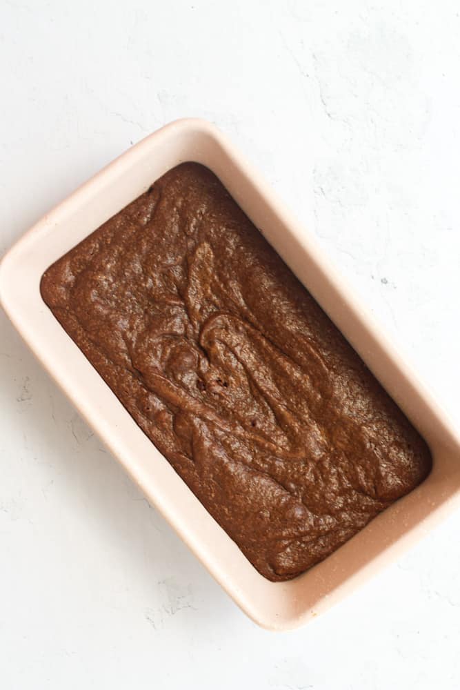 dairy free brownies baked in a pink loaf pan on a white backdrop.