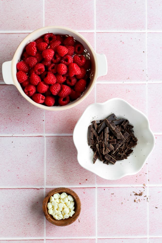 ingredients to chocolate coated raspberries on a pink backdrop