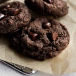 three eggless chocolate cookies on brown parchment paper.