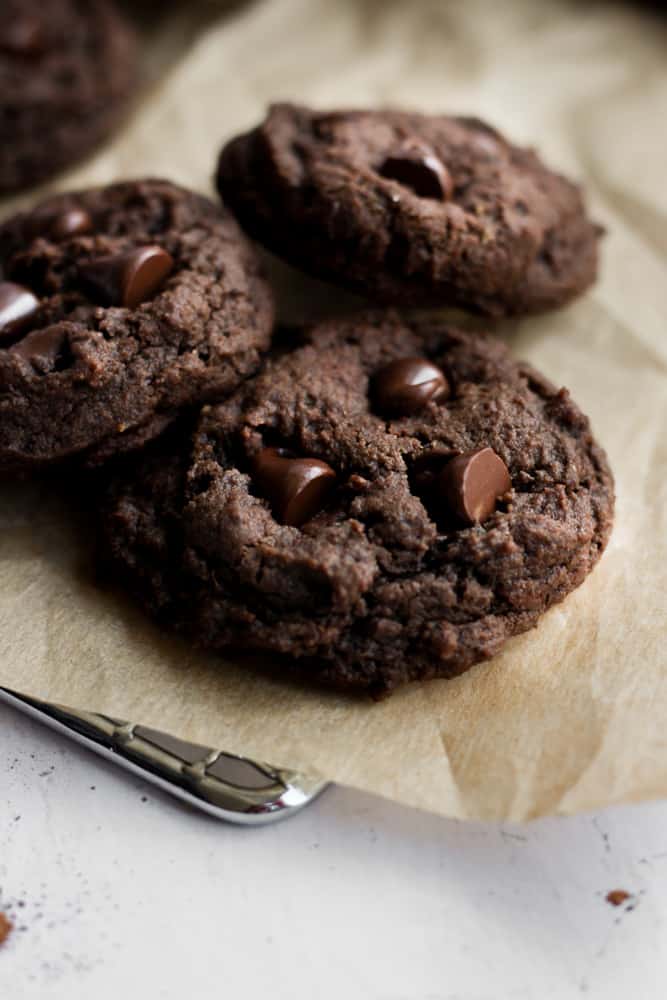 three eggless chocolate cookies on brown parchment paper.