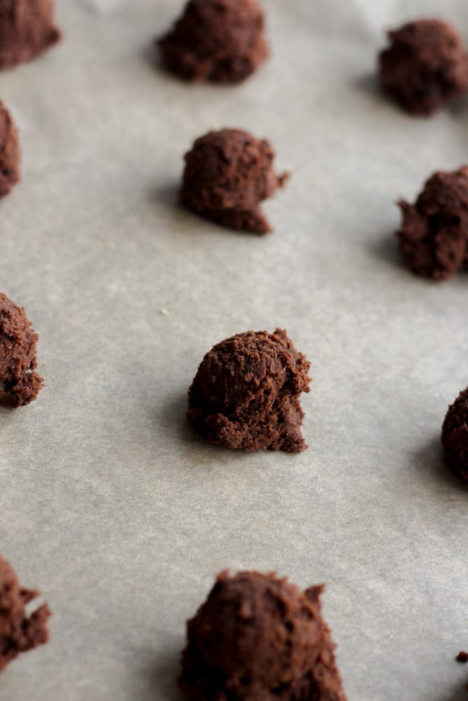 balls of chocolate cookie dough on parchment lined baking sheet.