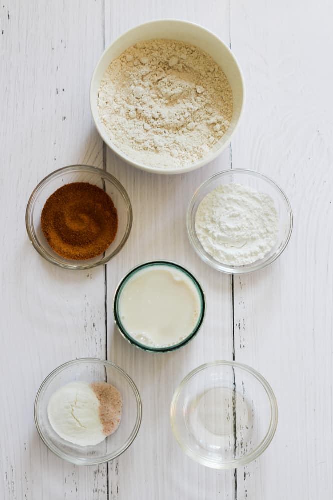 ingredients to make oat flour pancakes on a white backdrop.