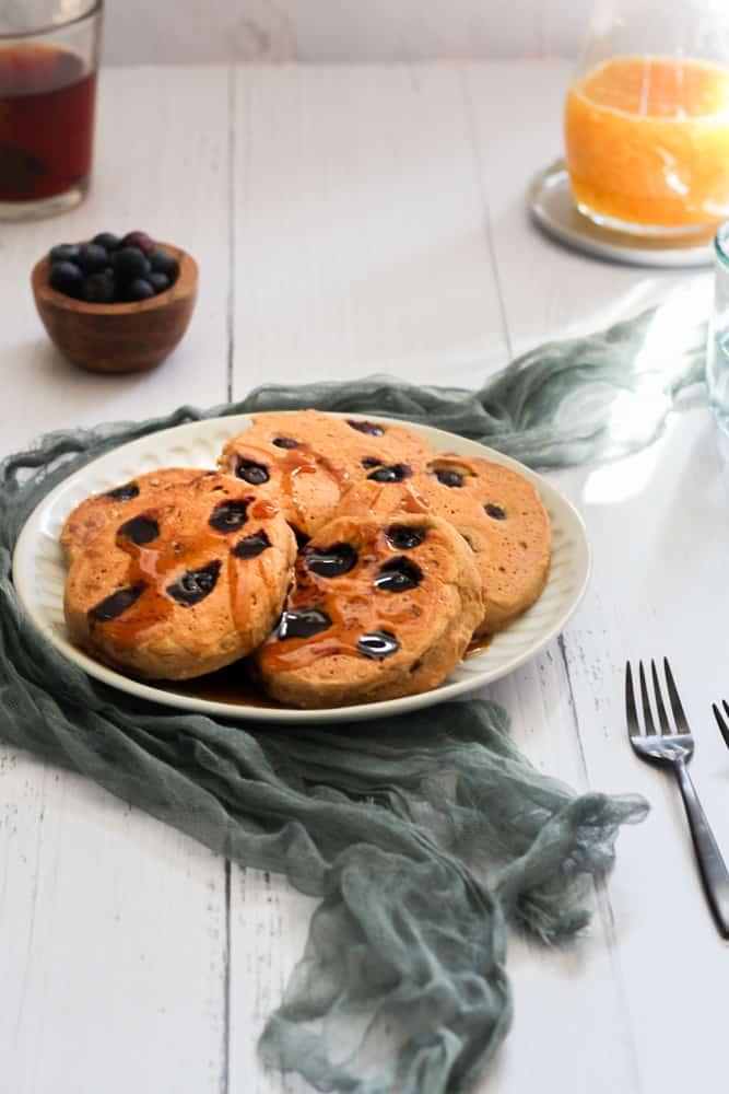blueberry vegan pancakes on a white plate with a gray linen napkin.