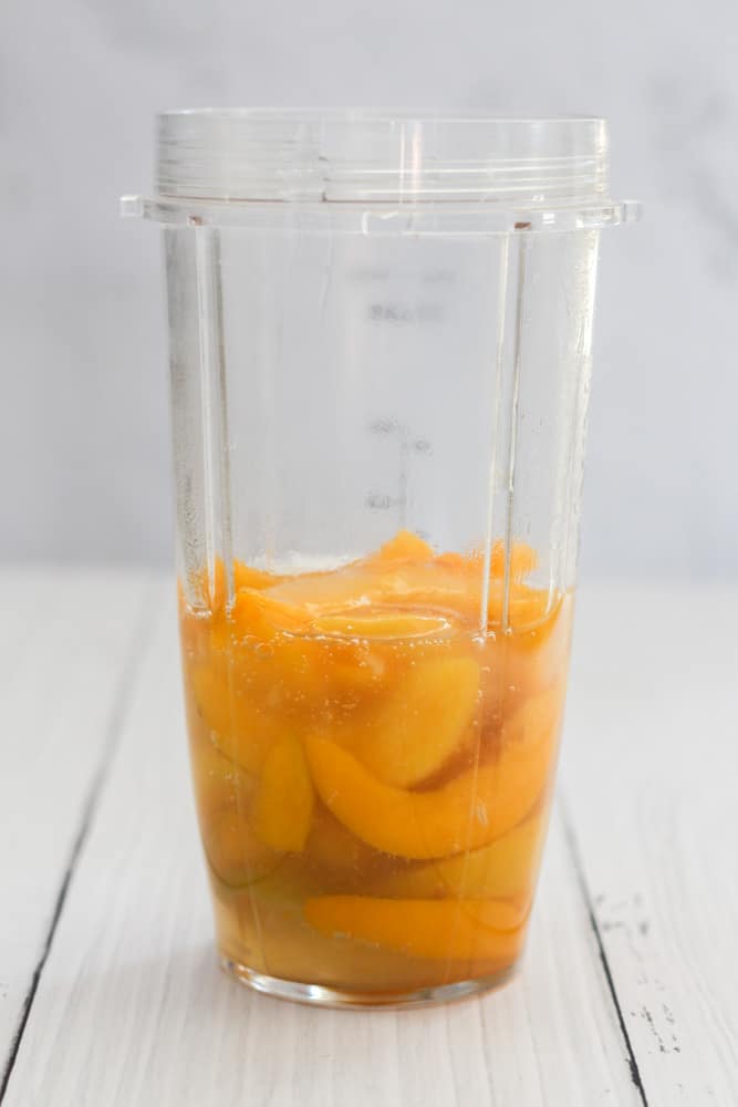 sugar free peaches in a blender on a white backdrop.