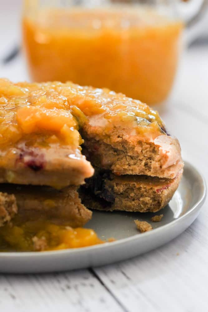 oat flour pancakes with a bite taken out topped with peach syrup.