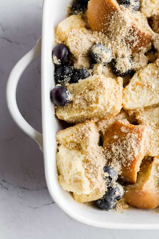 protein french toast casserole in a white baking dish with blueberries.