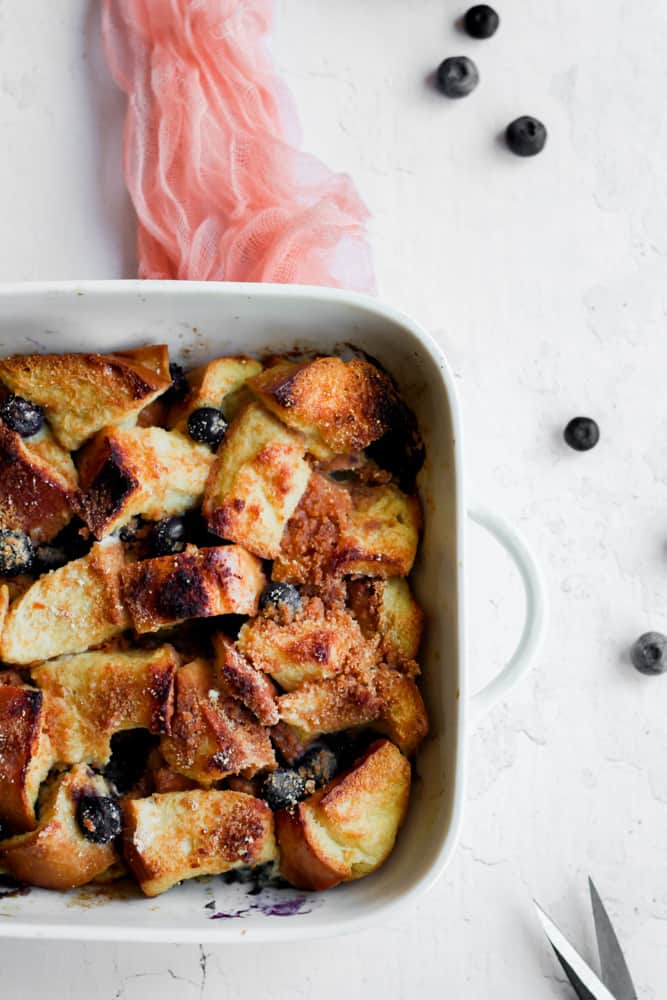 protein French toast casserole in a white baking dish on a pink napkin.