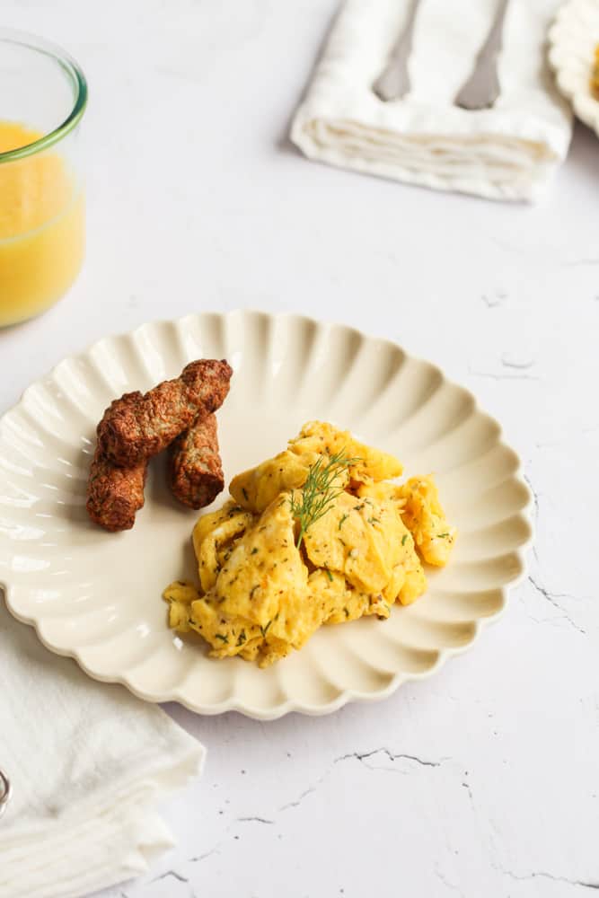 scrambled eggs without milk on a white plate with sausage links.