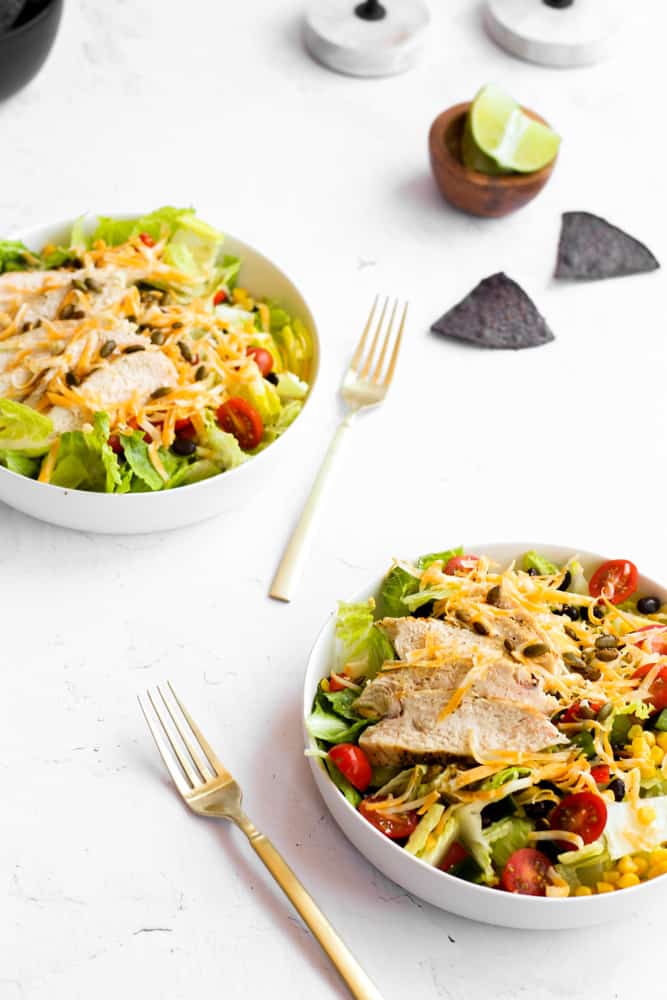 two white bowls with a southwest salad on a white backdrop.