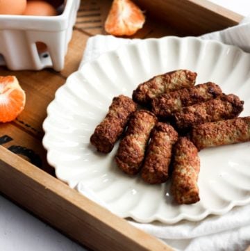 air fryer breakfast sausage on a white plate inside a wood serving tray with handles.