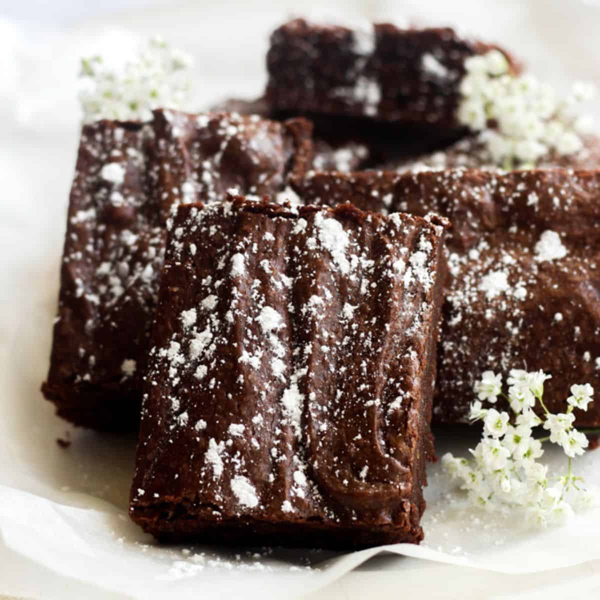 dairy free brownies dusted with powdered sugar on a white plate.