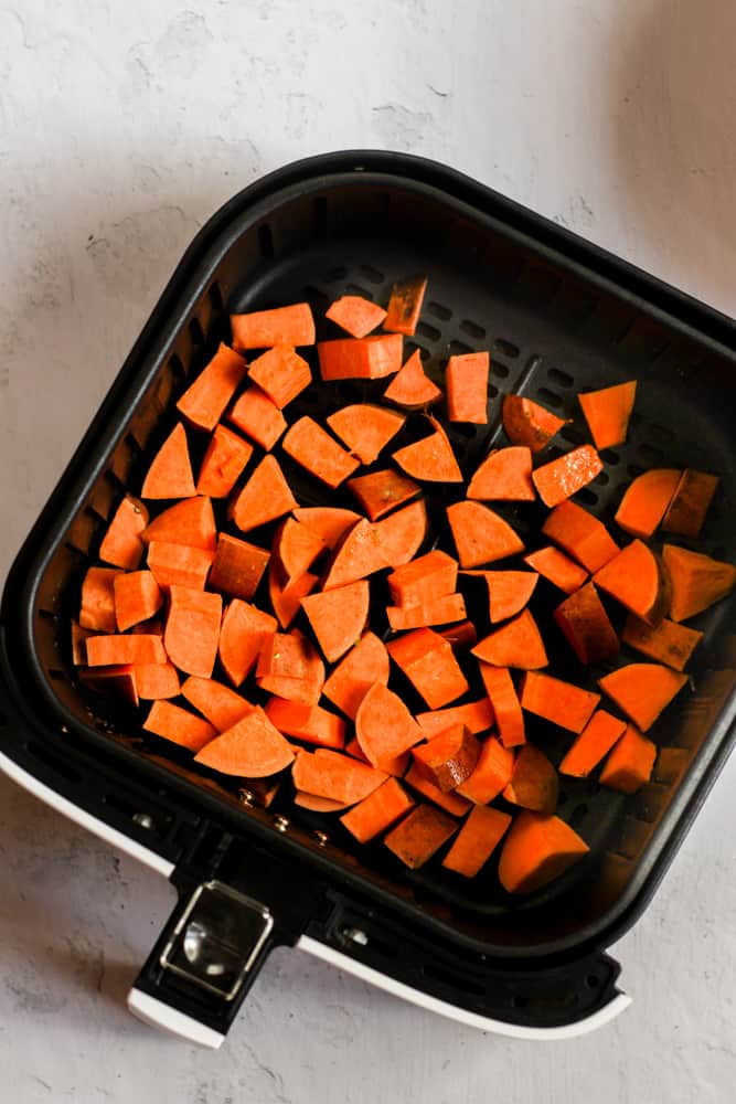 chopped sweet potatoes in an air fryer basket.