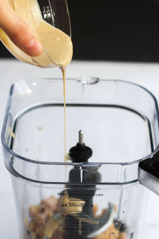 pouring tahini into a blender. 