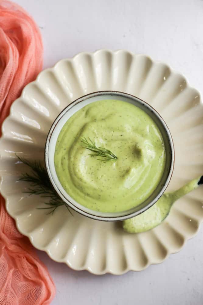 creamy avocado dressing in a bowl topped with fresh dill.