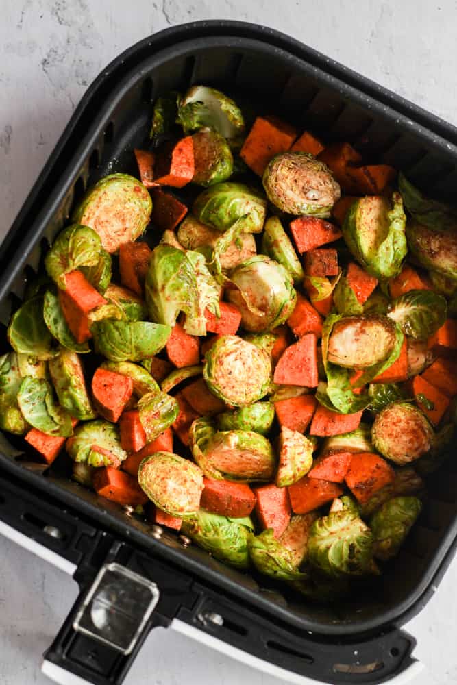 brussels sprouts and sweet potatoes in air fryer basket.