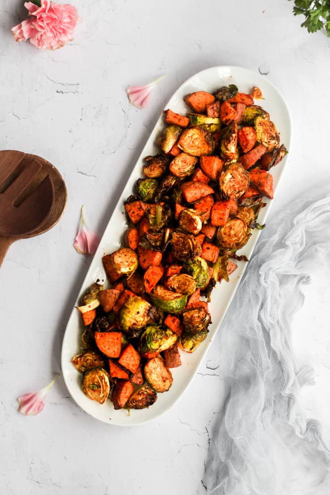 roasted brussels sprouts and sweet potatoes on a white serving platter.