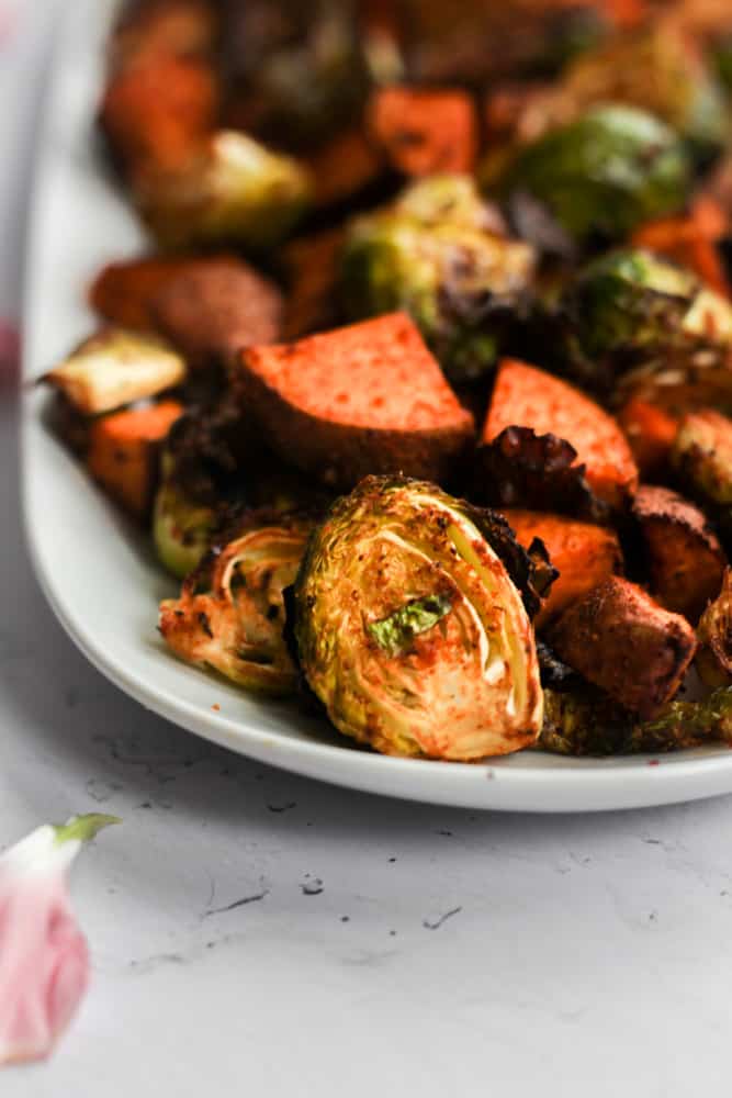 healthy air fryer roasted potatoes and sprouts on a white platter.
