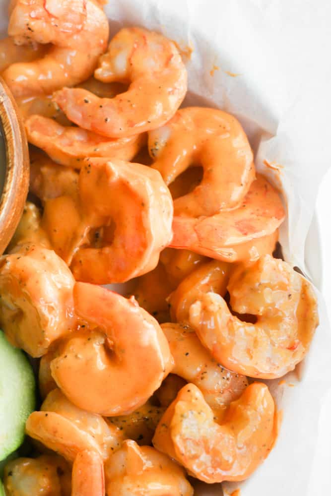 shrimp coated in buffalo sauce on parchment paper.