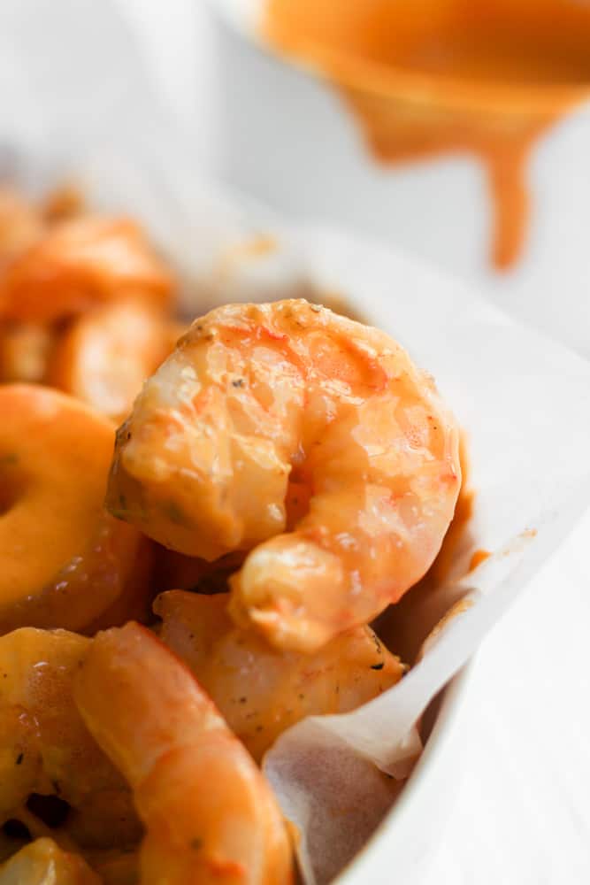 shrimp coated in buffalo sauce in a white bowl.