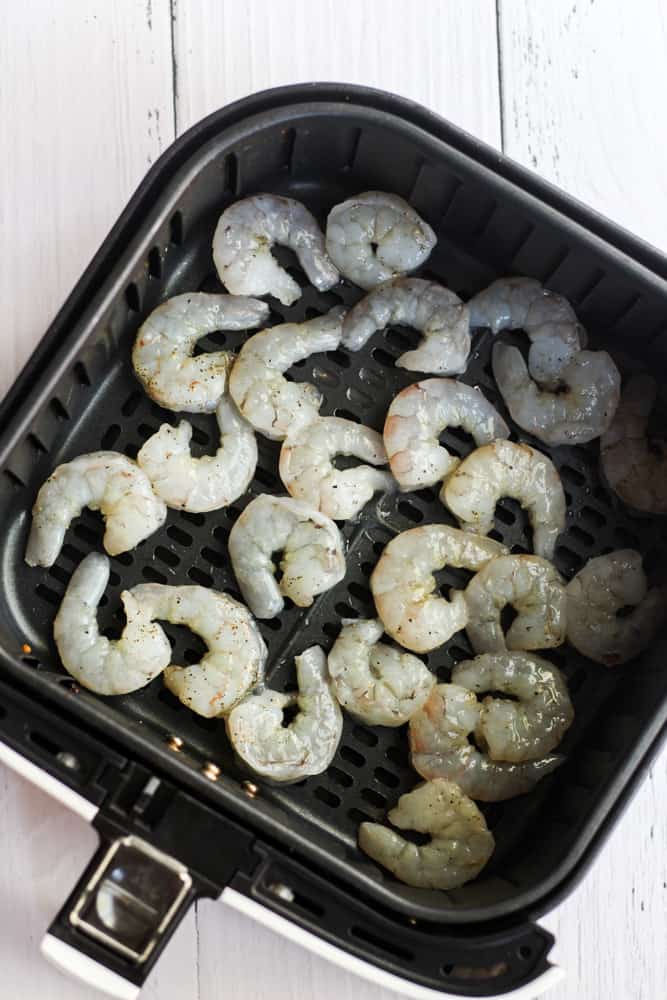 seasoned shrimp in the air fryer basket.