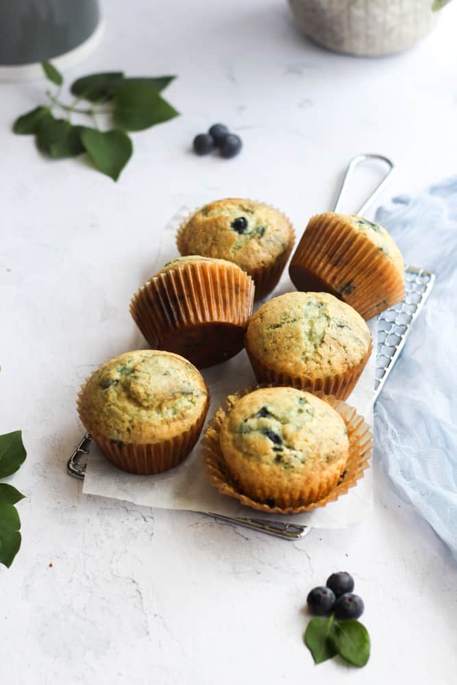 healthy blueberry muffins on a wire cooling rack with a blue napkin.
