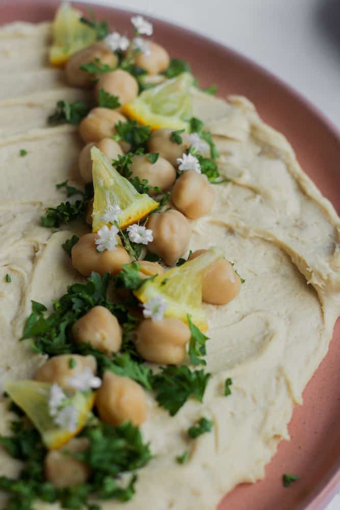 chickpeas and chopped herbs on healthy hummus platter.