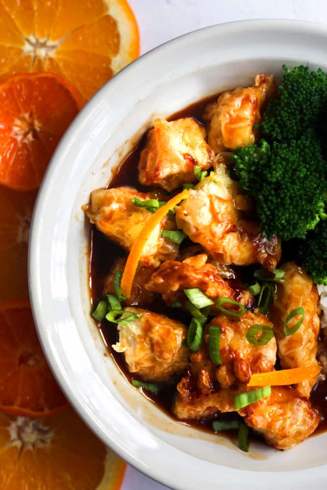 healthy orange chicken in a white bowl with broccoli.