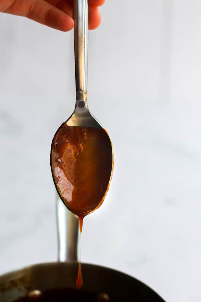 brown sauce dripping off a silver spoon.