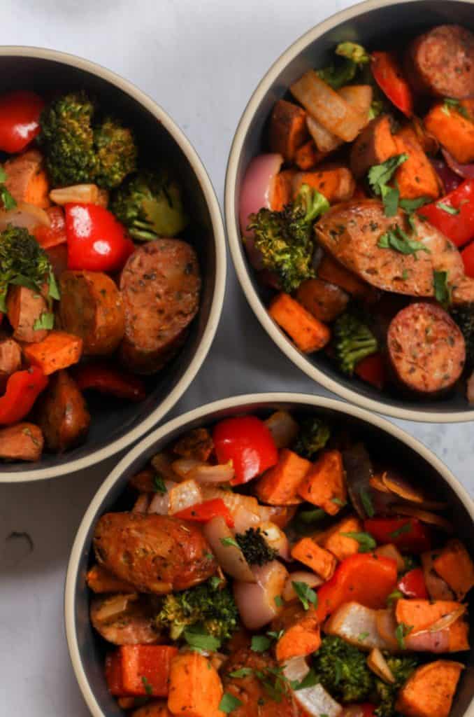 three dark gray bowls of air fryer chicken sausage and veggies.