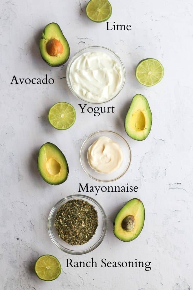 ingredients for avocado lime ranch dressing on a white backdrop labeled with black text.