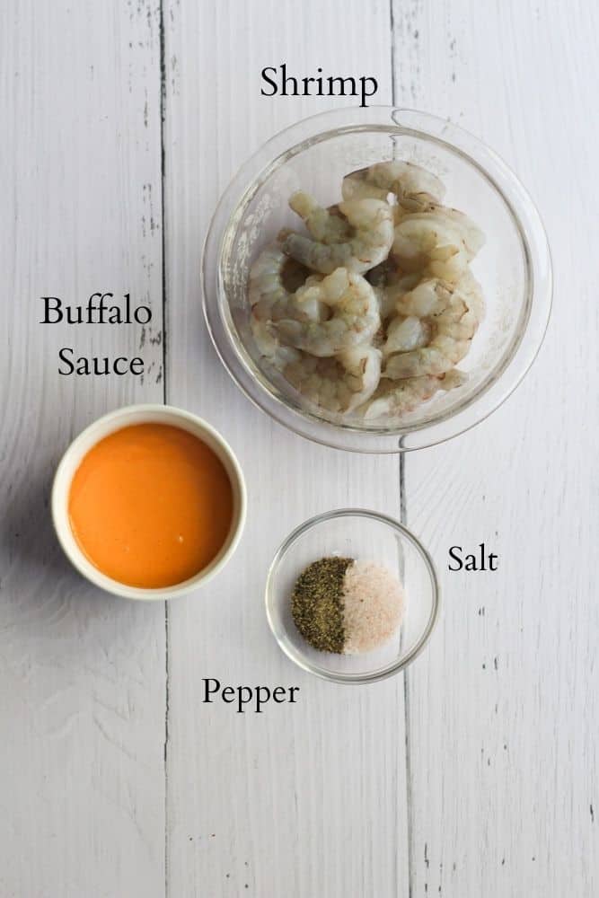 ingredients for buffalo shrimp labeled on a white backdrop.