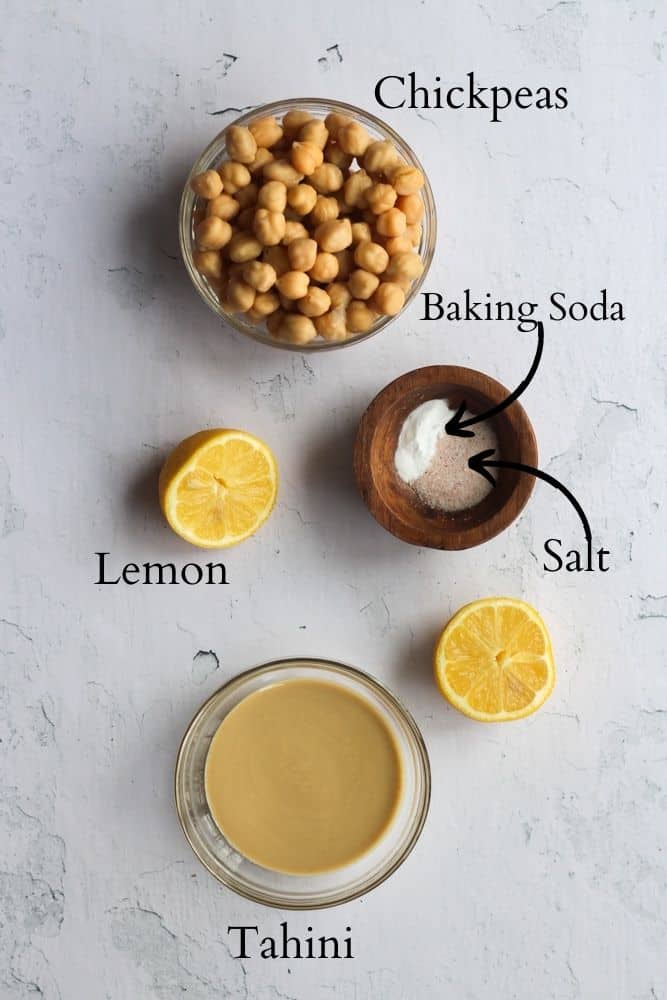 ingredients for oil free hummus on a white backdrop labeled with black text.