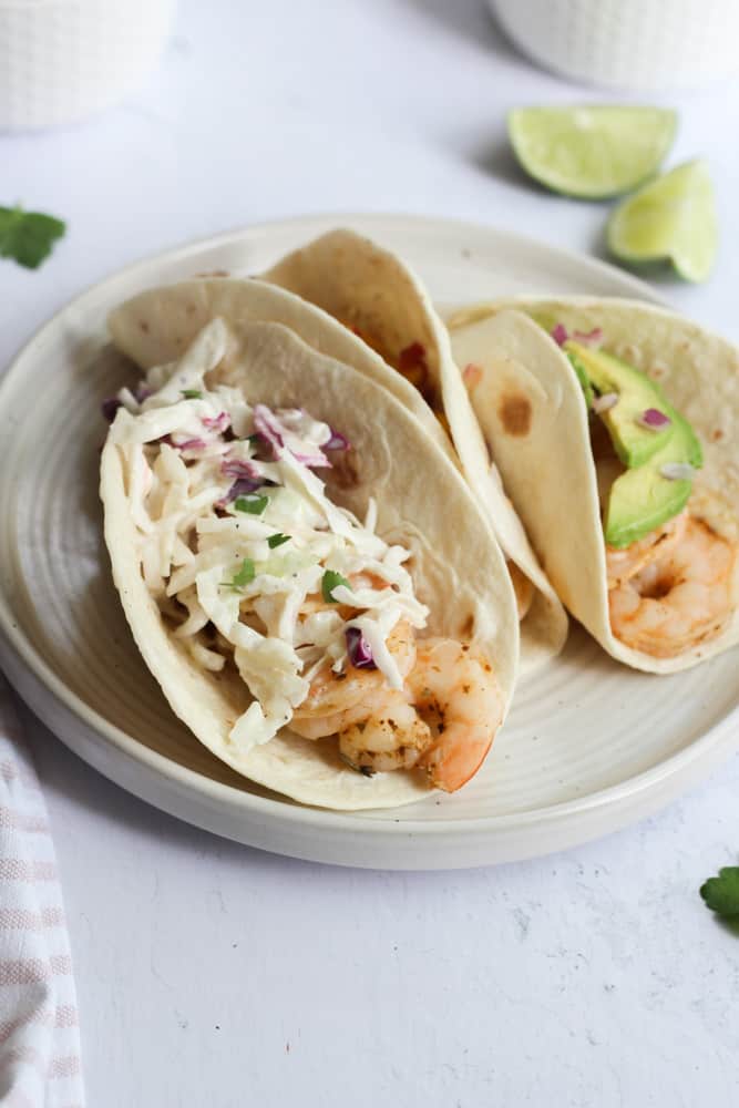 three air fryer shrimp tacos on a white plate.
