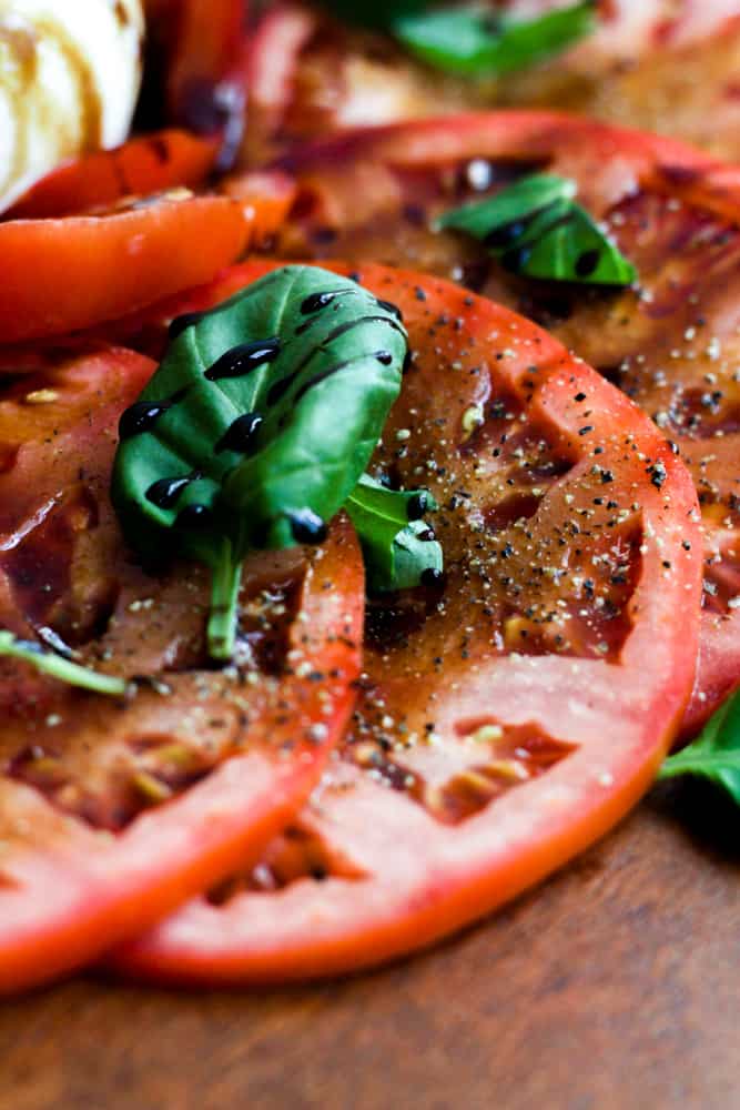 slices of tomatoes seasoned with salt and pepper, with fresh basil and balsamic glaze.