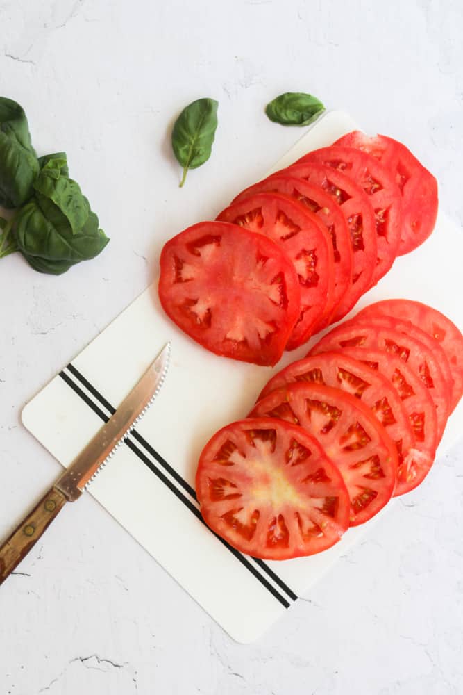 sliced tomatoes on a white cutting board.