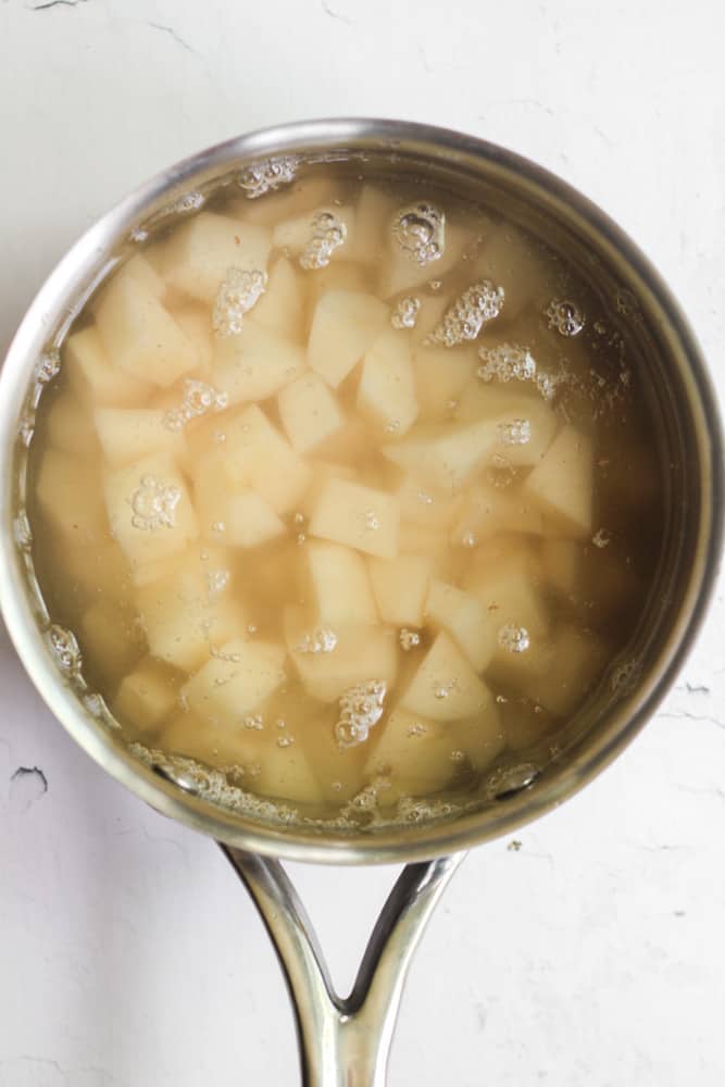 diced potatoes in a silver pot of water.