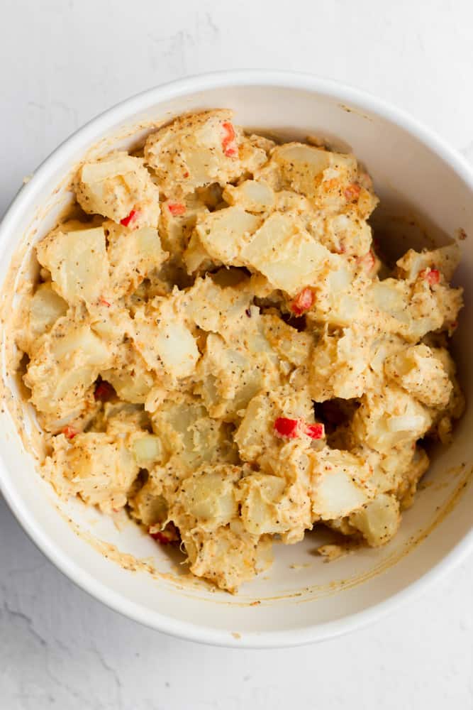 spicy potato salad mixed together in a white bowl.