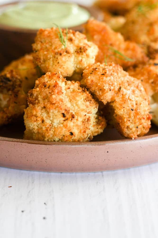 air fryer cauliflower bites topped with chopped herbs.