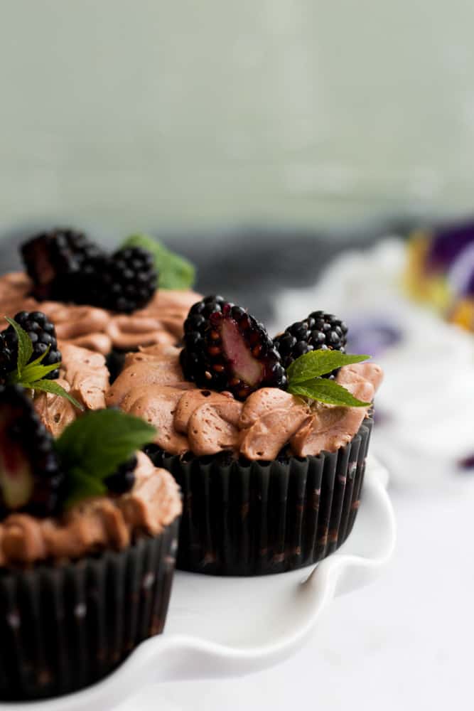eggless chocolate cupcakes topped with blackberries and chocolate frosting.
