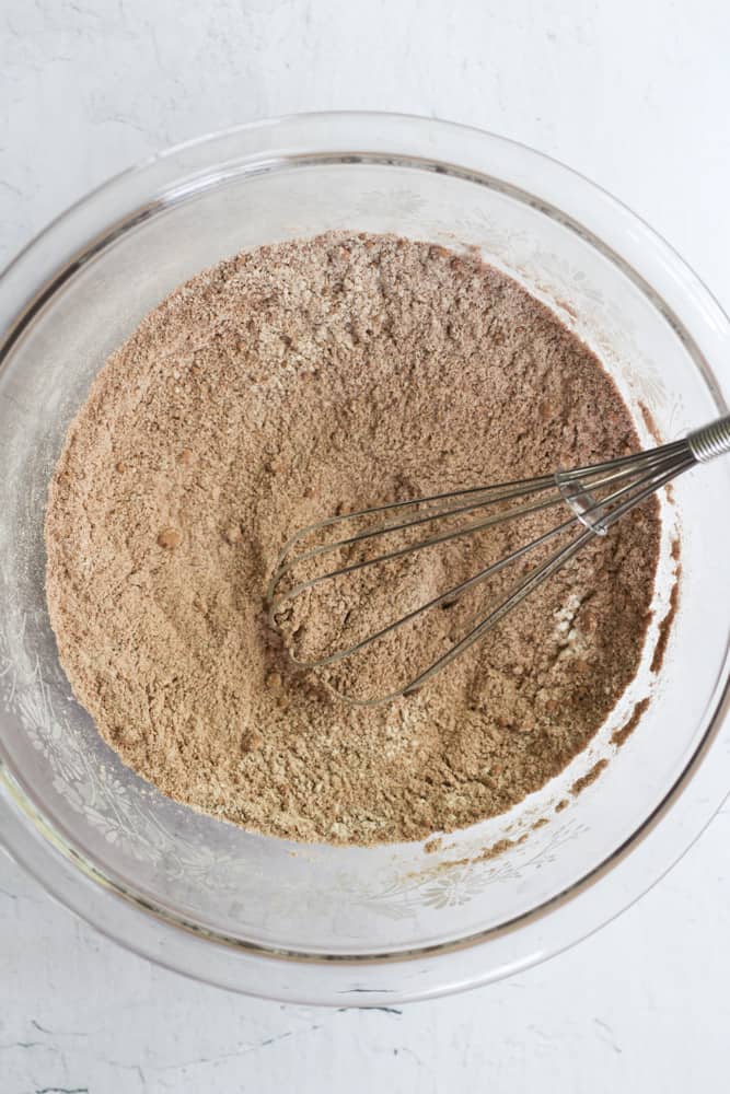 dry ingredients for eggless chocolate cupcakes in a clear bowl with a whisk.