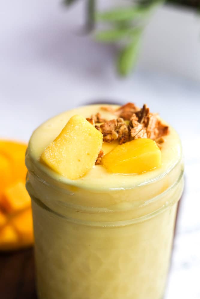 healthy tropical smoothie topped with mango and granola.