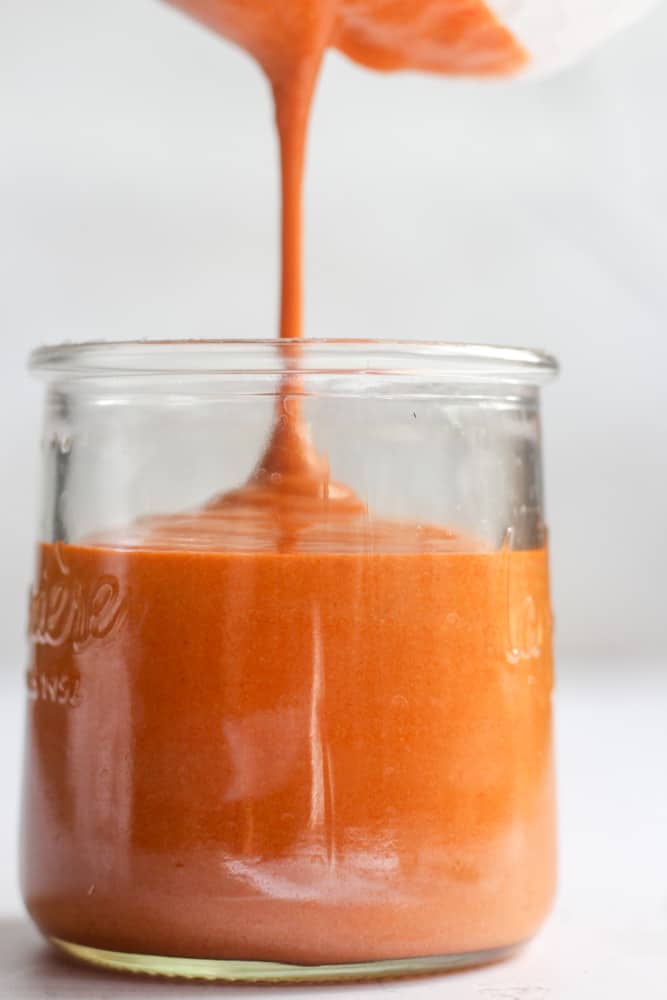 healthy buffalo sauce being poured into a glass jar.
