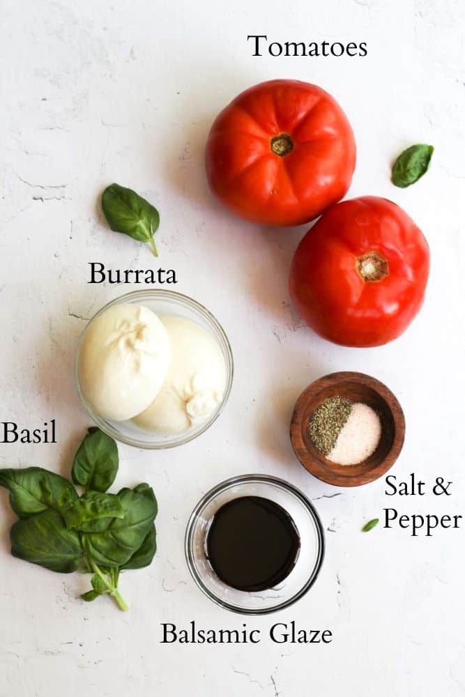 ingredients for burrata caprese salad on a white backdrop labeled with black text.